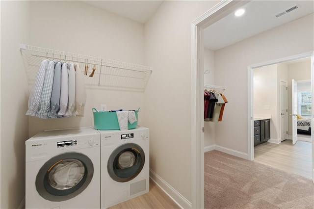 laundry area with light carpet, laundry area, visible vents, baseboards, and washing machine and dryer