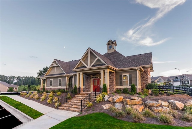 craftsman inspired home featuring stone siding and fence