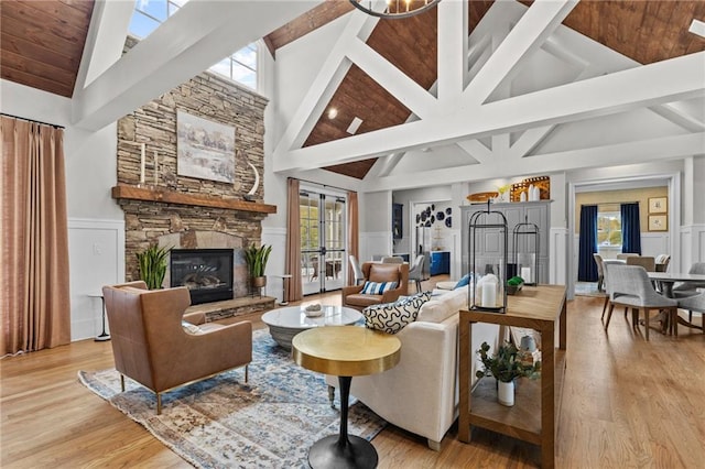 living area with light wood-style flooring, wainscoting, and a stone fireplace