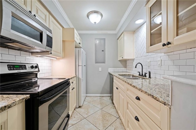 kitchen featuring light stone countertops, stainless steel appliances, crown molding, cream cabinetry, and a sink