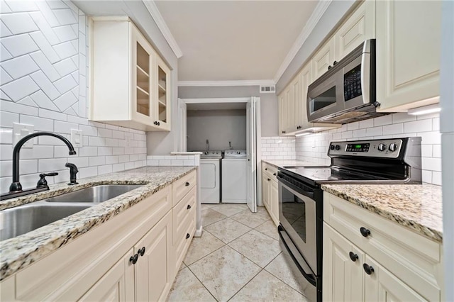 kitchen with stainless steel appliances, a sink, ornamental molding, decorative backsplash, and washing machine and clothes dryer