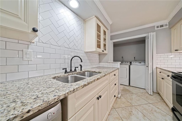 kitchen with ornamental molding, dishwasher, a sink, and washing machine and clothes dryer