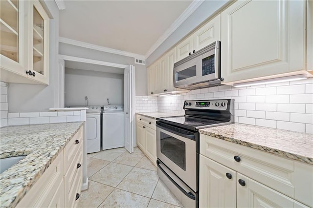 kitchen featuring tasteful backsplash, glass insert cabinets, ornamental molding, stainless steel electric stove, and separate washer and dryer