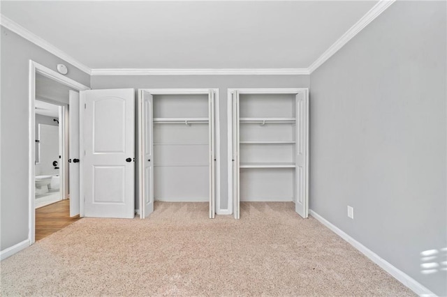 unfurnished bedroom featuring crown molding, carpet floors, baseboards, and multiple closets