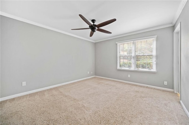 carpeted empty room with baseboards, ornamental molding, and a ceiling fan