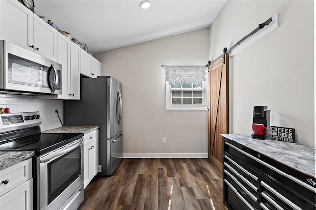 kitchen featuring appliances with stainless steel finishes, a barn door, white cabinetry, and light stone countertops