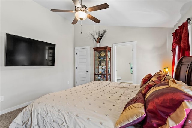 carpeted bedroom with ceiling fan, vaulted ceiling, connected bathroom, and baseboards