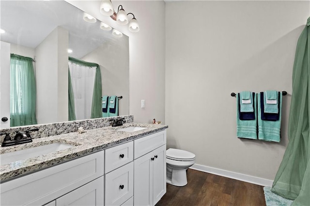 bathroom featuring double vanity, a sink, baseboards, and wood finished floors