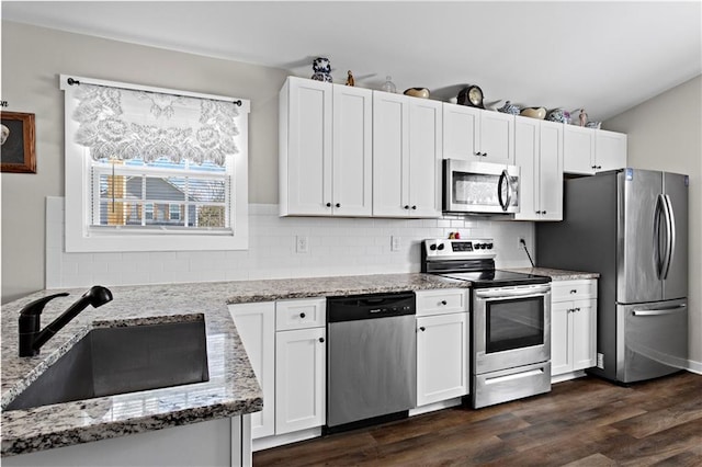 kitchen featuring stainless steel appliances, light stone counters, a sink, and white cabinets