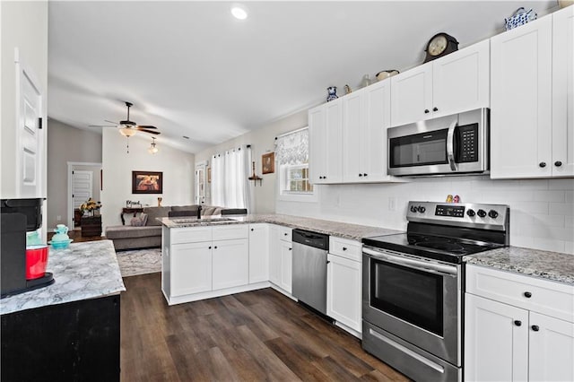 kitchen featuring appliances with stainless steel finishes, open floor plan, white cabinets, and a sink