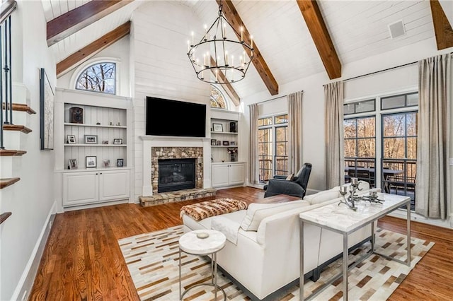 living area with baseboards, beamed ceiling, a stone fireplace, wood finished floors, and high vaulted ceiling