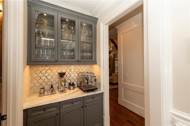 bar with crown molding, a decorative wall, decorative backsplash, a dry bar, and dark wood-style flooring