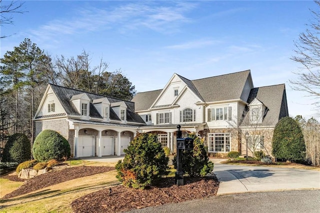 shingle-style home featuring a standing seam roof, stone siding, concrete driveway, and a garage