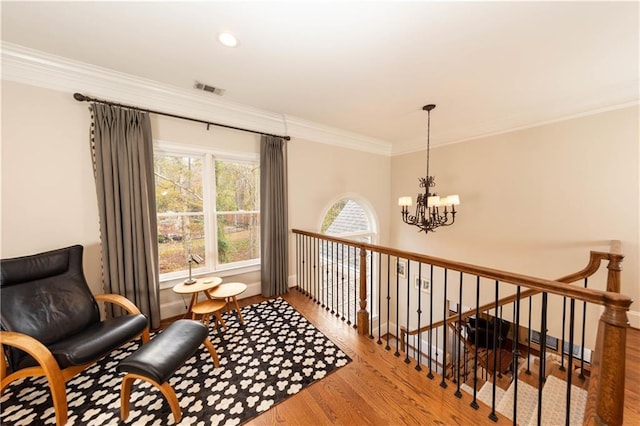 sitting room with visible vents, a notable chandelier, wood finished floors, crown molding, and baseboards