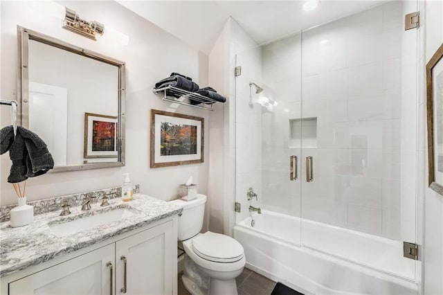 full bath featuring tile patterned floors, toilet, vanity, and shower / bath combination with glass door