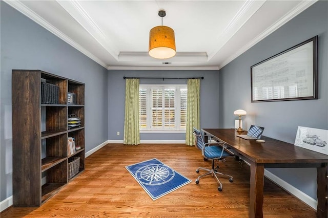 office space with crown molding, a raised ceiling, baseboards, and wood finished floors