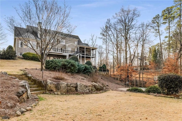 back of property featuring stairway, a wooden deck, a chimney, and a sunroom