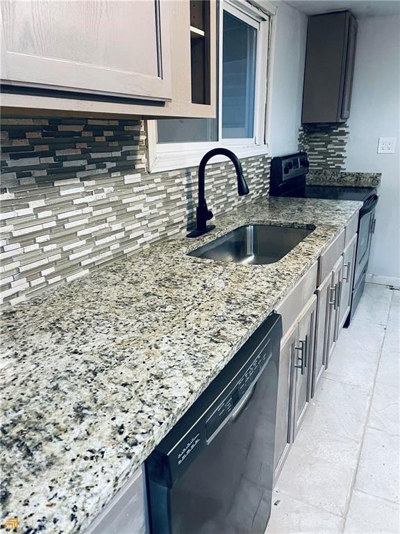 kitchen featuring light stone countertops, sink, decorative backsplash, and black appliances