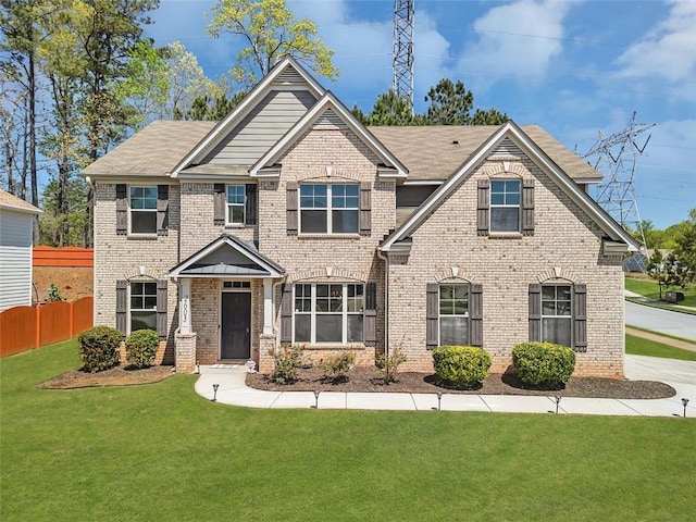 craftsman inspired home with a front yard, fence, and brick siding