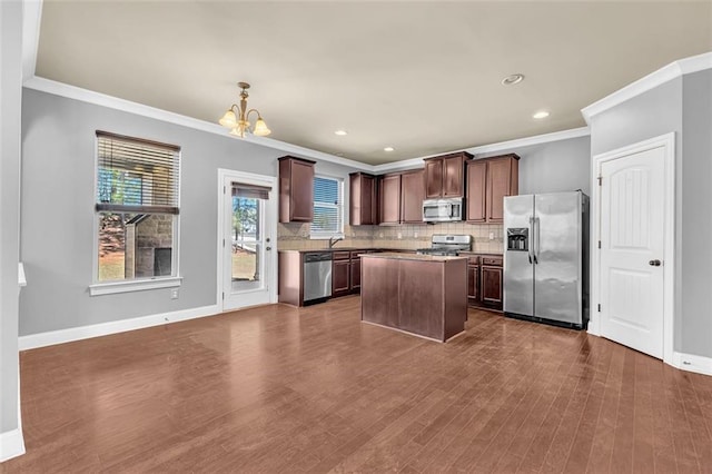 kitchen with stainless steel appliances, a notable chandelier, crown molding, and backsplash