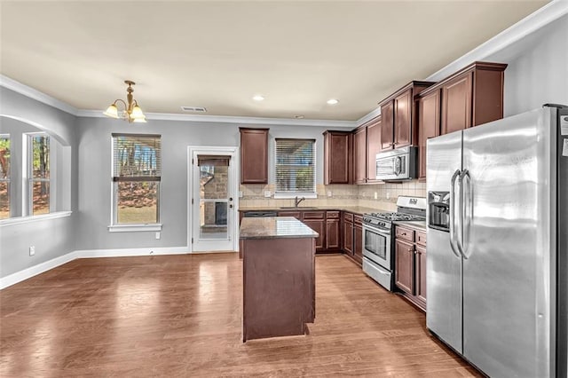 kitchen with ornamental molding, a healthy amount of sunlight, an inviting chandelier, and stainless steel appliances