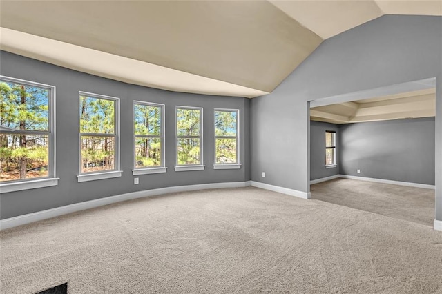 carpeted spare room with baseboards and lofted ceiling