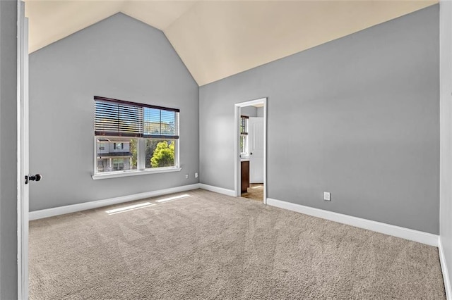 carpeted spare room featuring baseboards and high vaulted ceiling