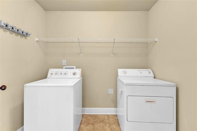 laundry area with light tile patterned floors, baseboards, separate washer and dryer, and laundry area