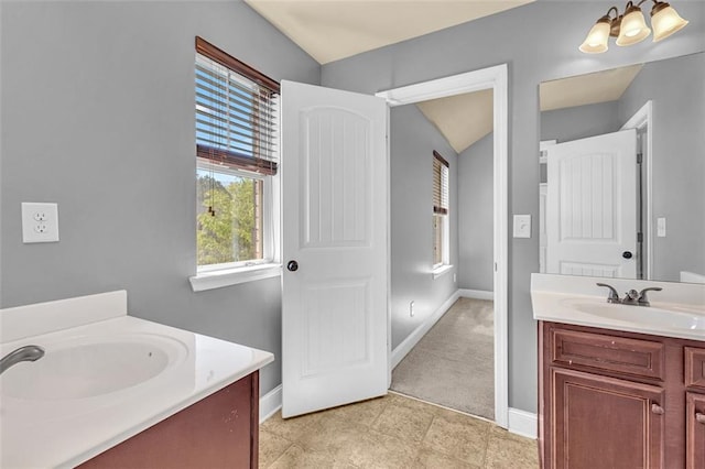 bathroom featuring vanity, baseboards, and vaulted ceiling