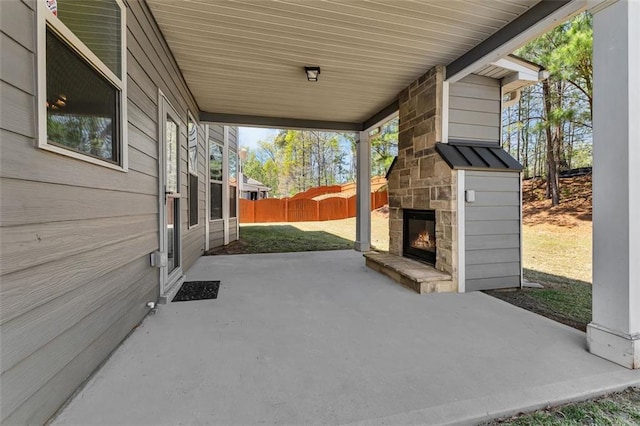 view of patio with fence and an outdoor stone fireplace