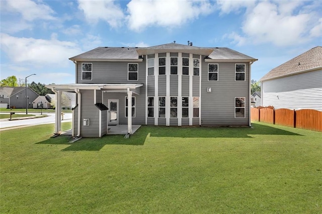 rear view of property featuring a yard, a patio area, and fence