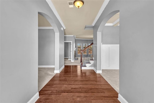 entrance foyer featuring arched walkways, visible vents, baseboards, and crown molding