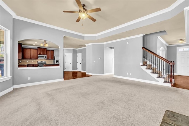 unfurnished living room with ornamental molding, dark carpet, baseboards, and ceiling fan