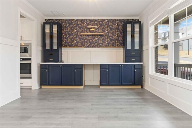 kitchen featuring stainless steel appliances, ornamental molding, blue cabinets, and light hardwood / wood-style floors