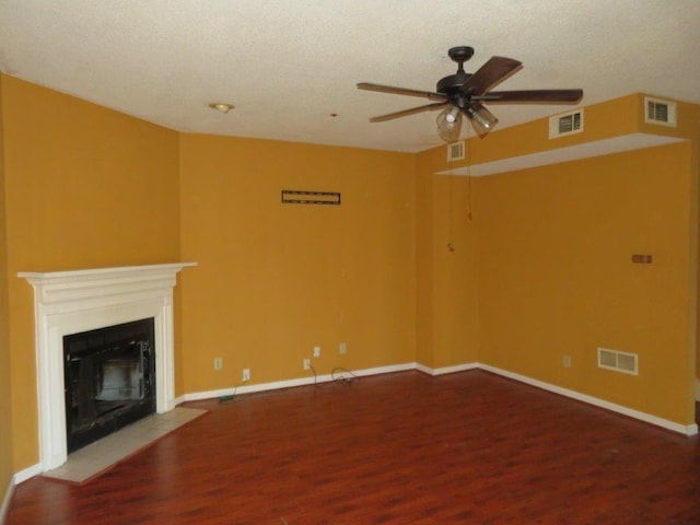 unfurnished living room with ceiling fan, wood finished floors, a fireplace with flush hearth, and visible vents