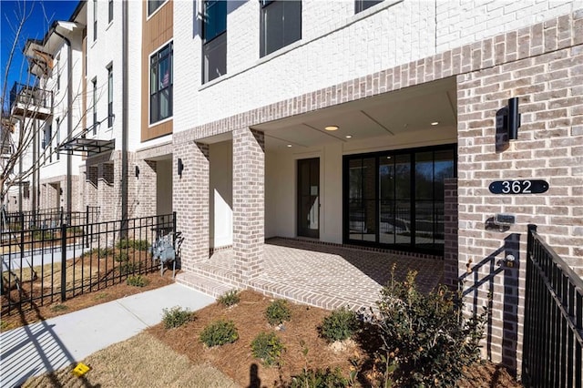 doorway to property with brick siding and fence