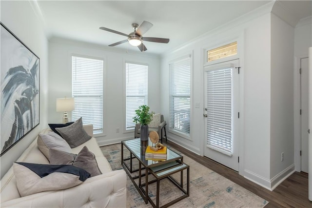living area featuring crown molding, ceiling fan, baseboards, and wood finished floors