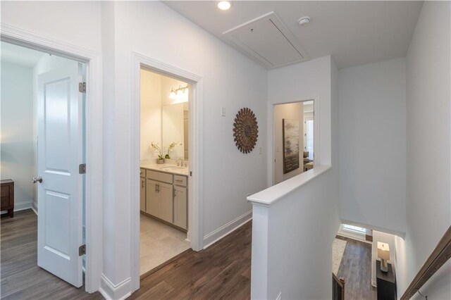 hall featuring attic access, a sink, dark wood-type flooring, recessed lighting, and an upstairs landing