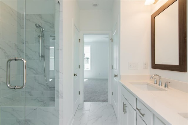 bathroom featuring a marble finish shower, marble look tile flooring, vanity, and baseboards