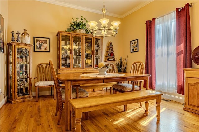 dining space with an inviting chandelier, ornamental molding, a wealth of natural light, and light hardwood / wood-style flooring