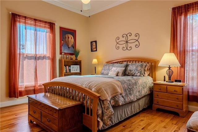 bedroom featuring ceiling fan, crown molding, multiple windows, and light hardwood / wood-style flooring