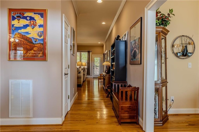 hall with crown molding and light hardwood / wood-style flooring