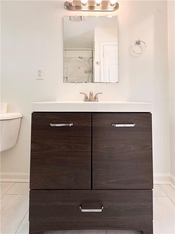 bathroom featuring walk in shower, vanity, tile patterned flooring, and toilet