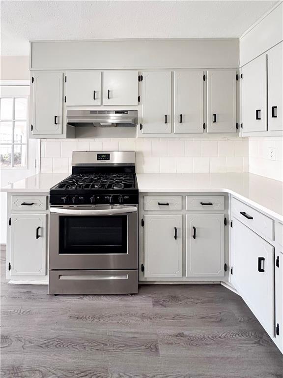 kitchen featuring light hardwood / wood-style flooring, decorative backsplash, gas stove, and white cabinets