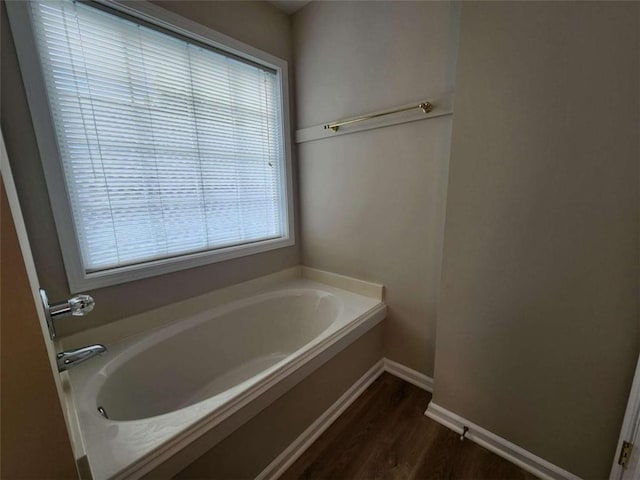 bathroom featuring a bath, a wealth of natural light, and hardwood / wood-style floors