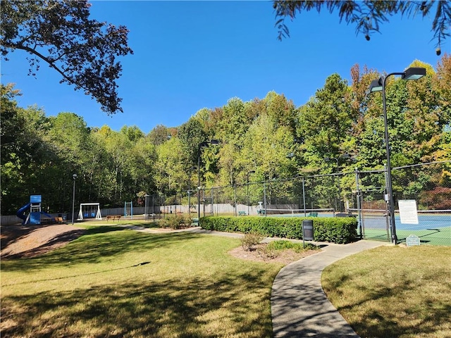 view of home's community featuring tennis court and a lawn