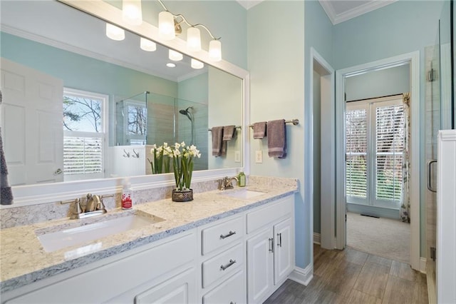 bathroom featuring a shower with door, ornamental molding, wood-type flooring, and vanity