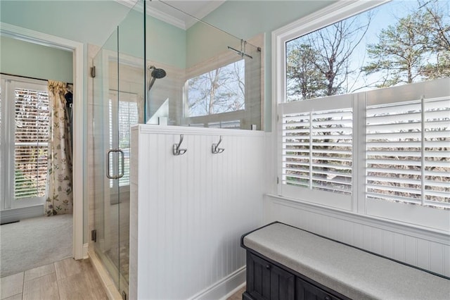 bathroom featuring crown molding, plenty of natural light, and a shower with shower door