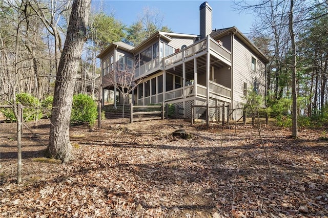 rear view of property featuring a sunroom and a deck