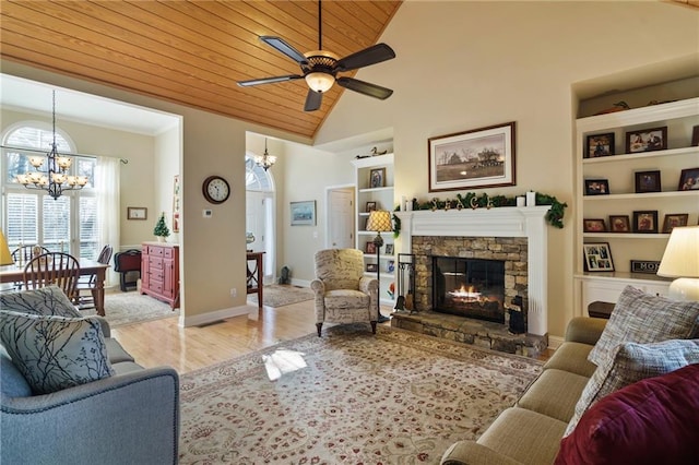 living room featuring wood ceiling, built in features, a fireplace, light hardwood / wood-style floors, and ceiling fan with notable chandelier